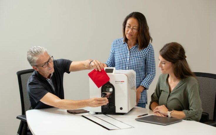 man measuring the color of a red object with spectrophotometer