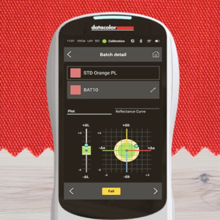 Portable spectrophotometer doing color quality control on a orange and red textile swatch